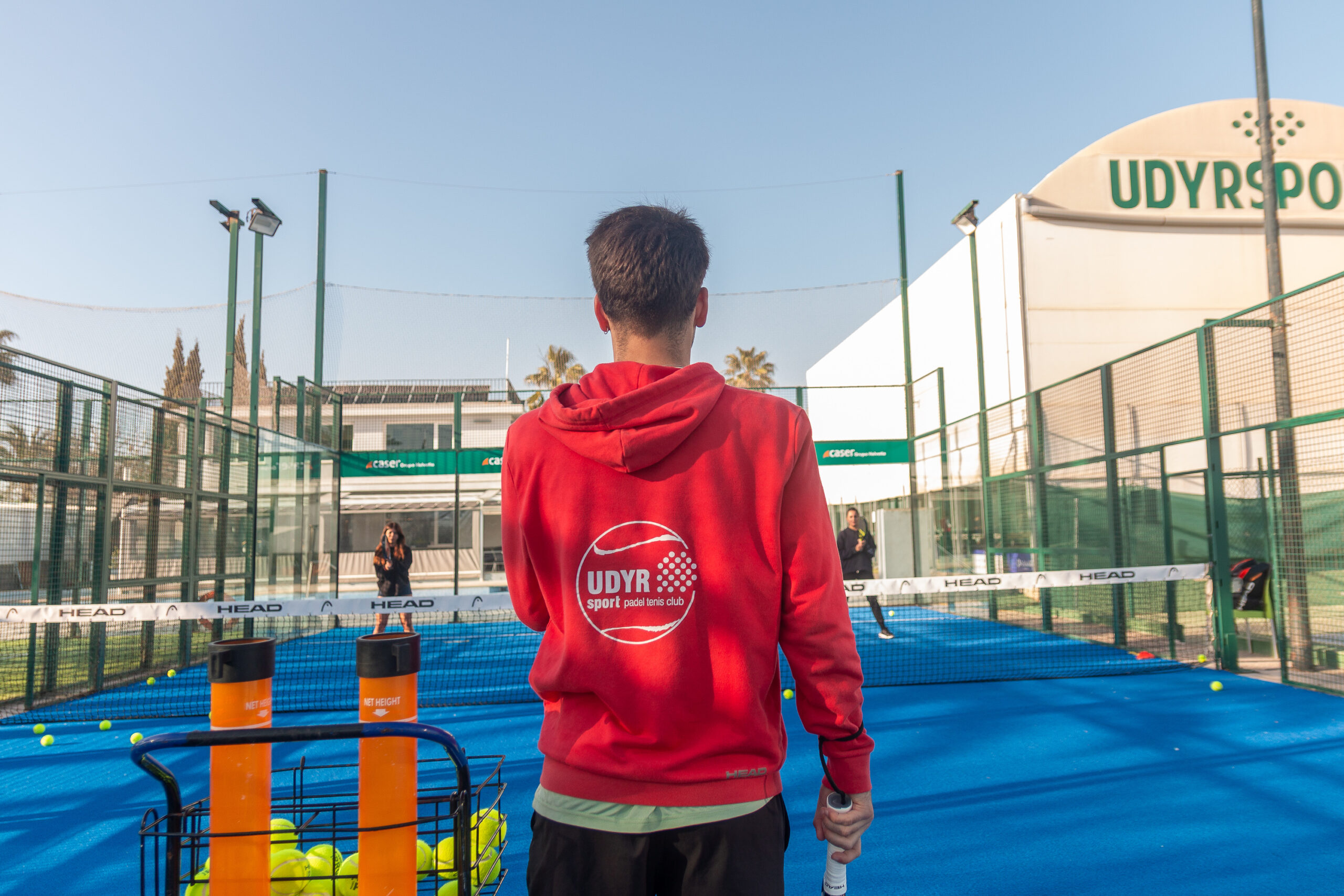 profesor de padel de espalda entrenando con dos mujeres