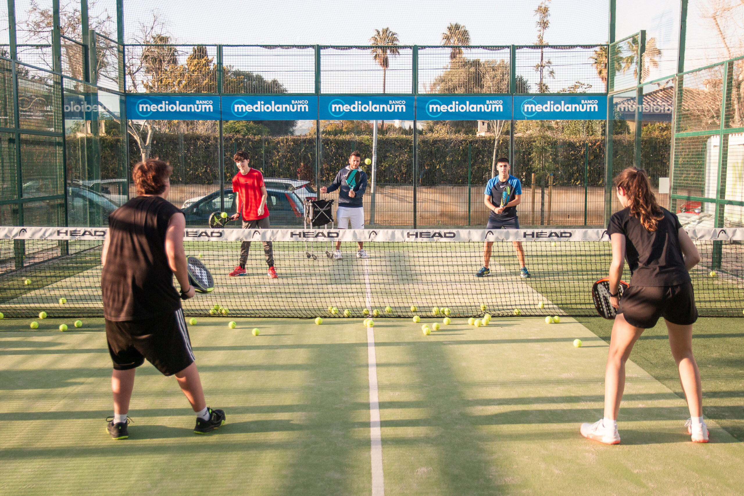 grupo de niños y profesor entrenando al padel